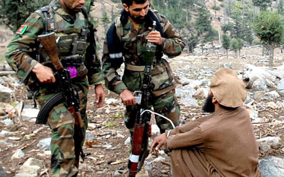 Afghan soldiers question a man found wandering near the site of an attack on a U.S. outpost in northeastern Afghanistan.