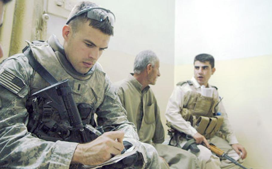 U.S. Army 1st Lt. Michael Smith, left, a platoon leader in 4th Infantry Division’s Company A, 1st Battalion, 8th Infantry Regiment, takes notes as Iraqi army 2nd Lt. Brosk talks with a man in eastern Mosul’s Wahda neighborhood.