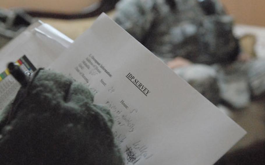 Second Lt. Scott Dawe fills out a displaced-persons form Thursday while collecting information from families who are returning to Baghdad’s Ghazaliya neighborhood.