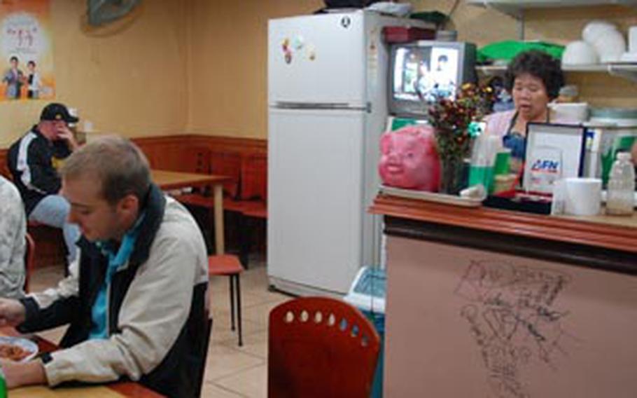 Airmen from Kunsan Air Base eat dinner at the Big Boy Restaurant in America Town as the South Korean owners clean up at the counter behind them. Gunsan City recenty renamed the area "International Culture Ville" in hopes bringing new development to the bar and restaurant district.