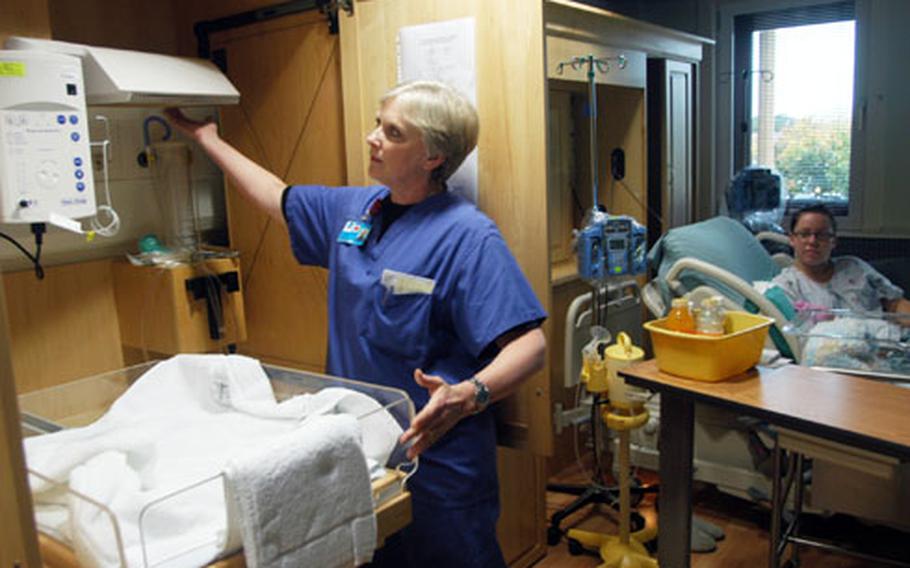 Capt. Vivian Newport, a nurse, pulls out a baby warmer from behind wooden cabinets inside one of seven new birthing rooms at the RAF Lakenheath hospital.