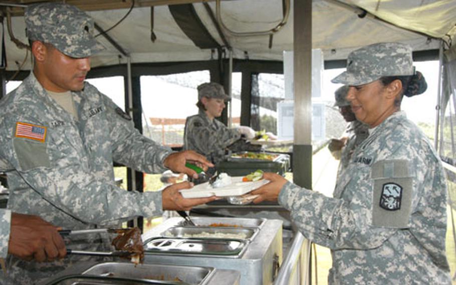 Spc. Joe Tapia, a food specialist with the 1-1 Air Defense Artillery Battalion, serves a scoop of garlic mashed potatoes Tuesday to Spc. Dawn Lee at Torii Station, Okinawa
