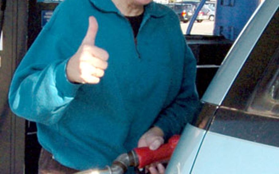 DODDS teacher Susan Sampson expresses her satisfaction about the lower gas prices as she fuels up Friday on Yokosuka Naval Base, Japan.