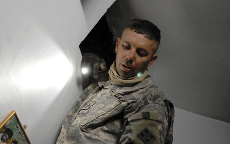 Staff Sgt. John Hardin searches a crawl space of a home in Baghdad during a Sunday raid that netted an assassination ring suspect.