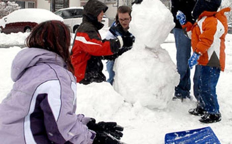 Rebekah Wilson, Kevin Godert, Geneva Nemier, Amber Wilson and Christopher Wilson, from left, build a snowman at Wetzel housing area in Baumholder