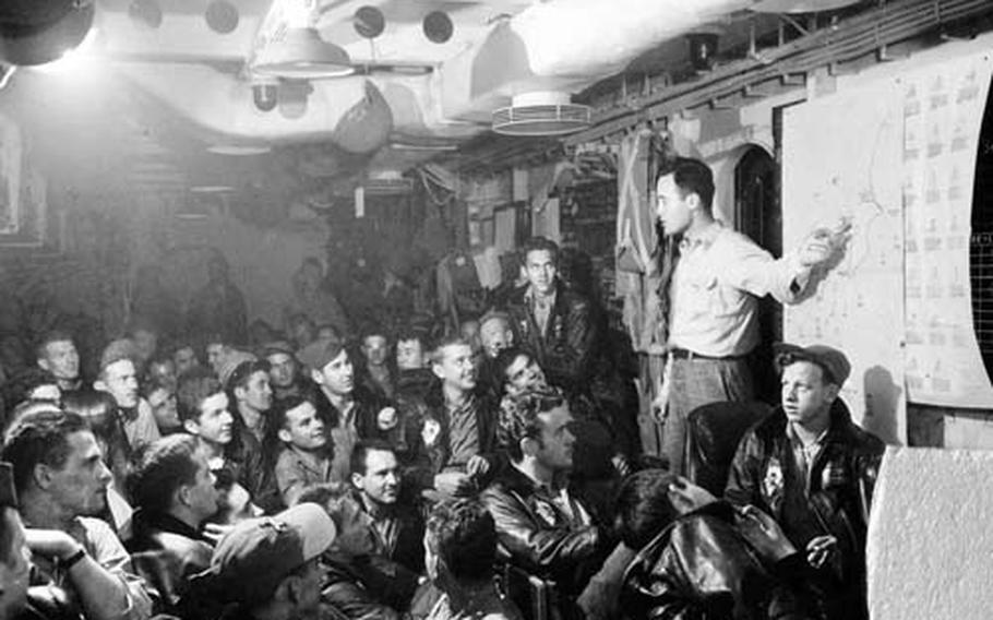 J. Waite "Slabo" Bacon, torpedo squadron intelligence officer, briefs pilots and crew in their ready room before a strike. The room was blown apart when Ogawa&#39;s plane crashed into the Bunker Hill.