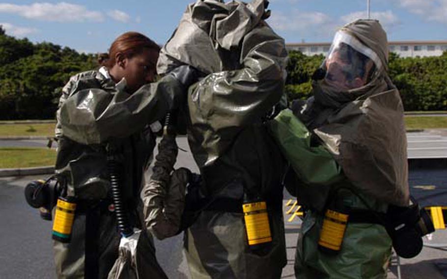 Senior Airman Jazmine Clark, left, Staff Sgt. Keneisha Fuller, center, and Staff Sgt. Jeanett Vielman, all of the 18th Medical Group, suit up for a decontamination drill Thursday at Kadena Air Base on Okinawa. The exercise involved cleaning up victims exposed to hazardous chemicals. Thousands of airmen in the 18th Wing were participating in emergency response drills as part of a weeklong Operational Readiness Exercise.