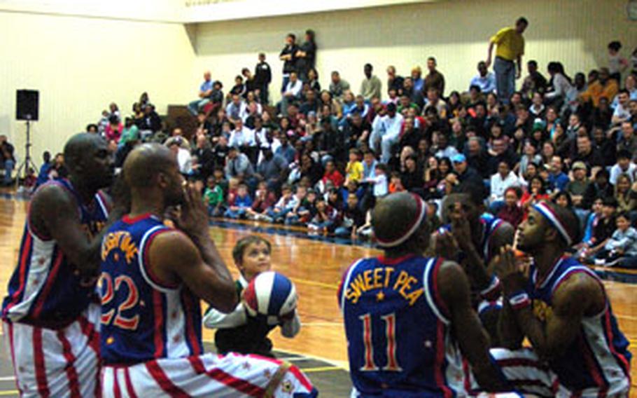 Members of the Harlem Globetrotters offer prayers as a young member of the audience prepares to take a shot Friday night Yokota Air Base’s Samurai Fitness Center. The Globetrotters visited Yokota as part of their holiday tour of military bases throughout the Pacific.