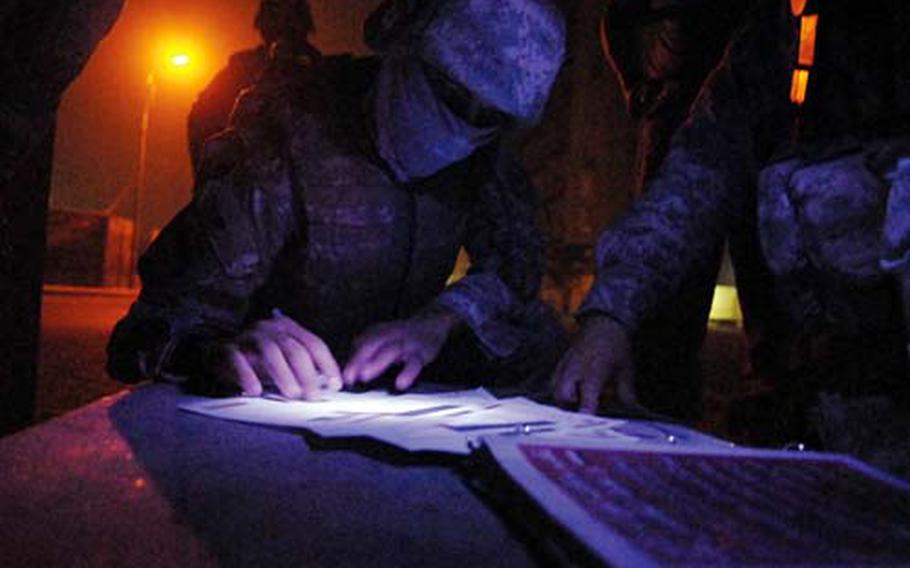 A masked interpreter translates some documents for an American patrol in Baghdad.