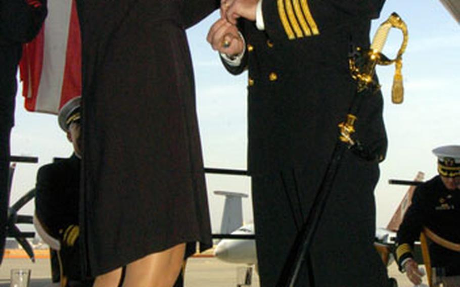 Amy Gardner fastens a pin on the uniform of her husband, Capt. Eric W. Gardner, during Thursday’s change of command ceremony aboard Naval Air Facility Atsugi, in which Gardner become the base’s new commanding officer.