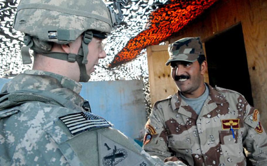 Second Lt. Clayton Merkley shakes hands with Iraqi army 1st Sgt. Hassan al-Harabi after inspecting his checkpoint Friday in Baghdad’s Sadr City district. Merkley’s unit — Company C, 1st Battalion, 35th Armor Regiment — requires every patrol to either include Iraqi soldiers or to check up on Iraqis to make sure things are proceeding well.