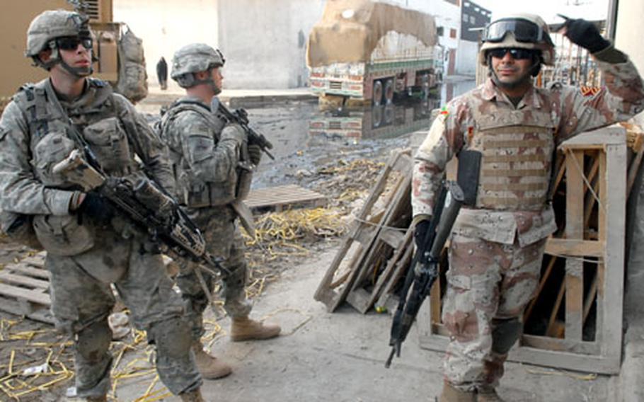 Iraqi army Cpl. Abbas Kadim tells U.S. soldiers to head to another door while searching businesses Saturday in Baghdad’s Sadr City district.