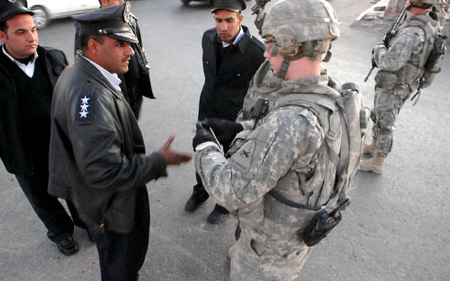Second Lt. Clayton Merkley listens to Iraqi police complain about manpower problems Friday at a checkpoint in Baghdad’s Sadr City district.