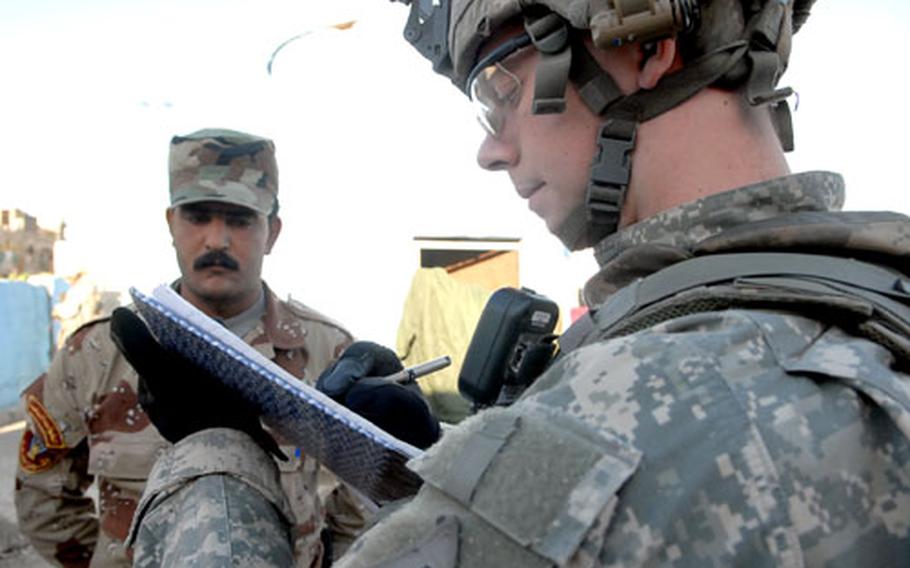 Second Lt. Clayton Merkley signs a guestbook Friday at a checkpoint in Baghdad’s Sadr City district while Iraqi army 1st Sgt. Hassan al-Harabi looks on. The guestbook allows visitors to record the soldier’s performance when they pass through. Merkley’s verdict: The checkpoint was pretty good, but the soldiers could search the passing cars a bit better.