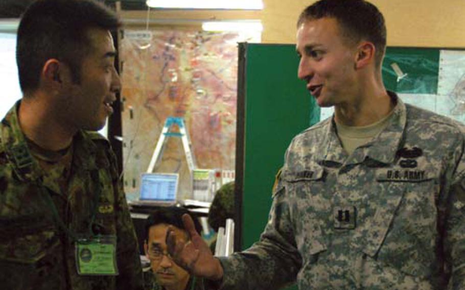 Japan Ground Self-Defense Foce Capt. Naoki Kobayashi, left, and U.S. Army Capt. Bryan Dunker chat Friday during the 2008 Yama Sakura exercise at Camp Asaka, Japan.