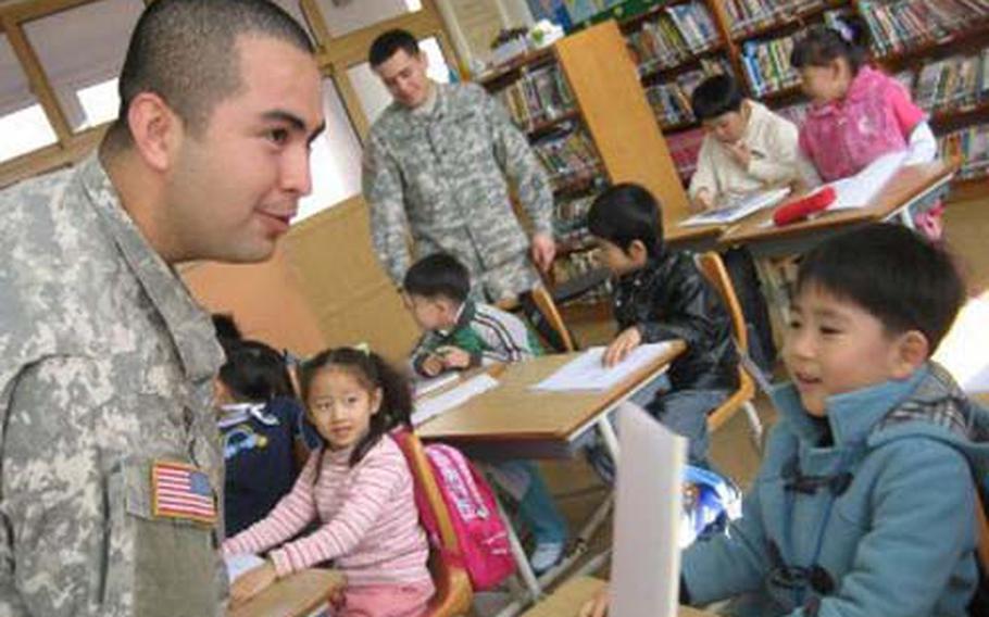 Soldiers stationed at Camp Carroll, South Korea, work with students at the Gwanho Elementary School near the base. Camp Carroll soldiers have been volunteering at the school since last year. Their efforts helped the small school remain open.