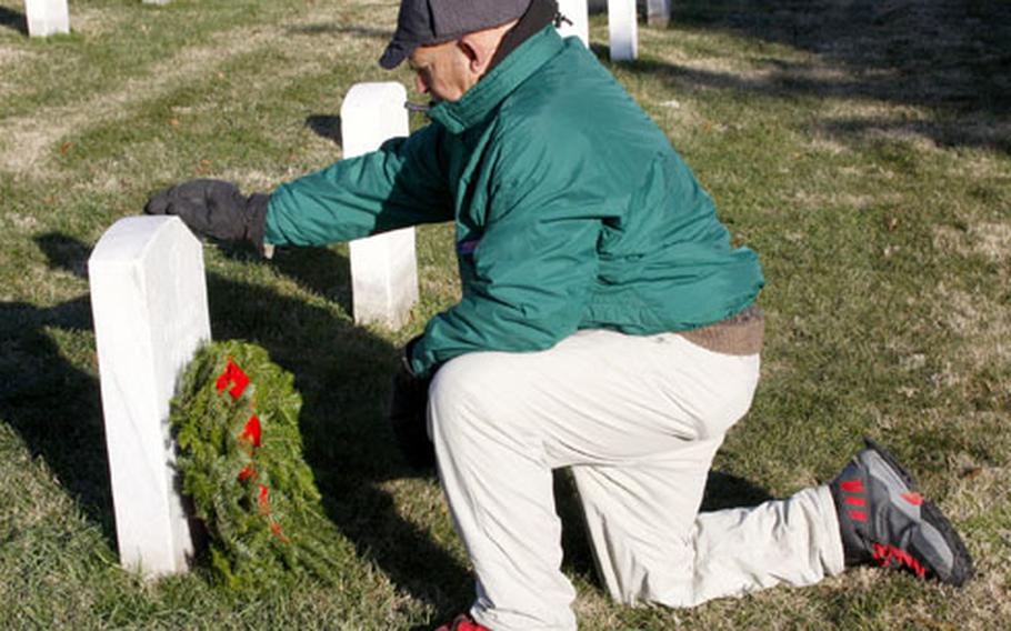 Ed Enamait pauses after placing a wreath on a grave at Arlington National Cemetery on Saturday.