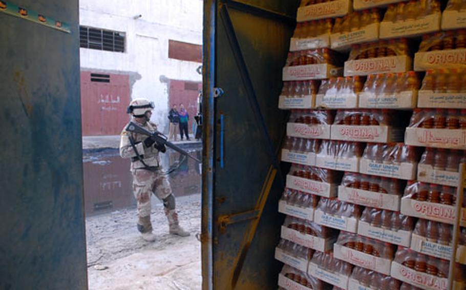 raqi army Cpl. Abbas Kadim waits outside of a building used to store juice during a search of a factory neighborhood near Sadr City’s Jamilla market on Saturday. The district has many machine shops that soldiers searched for roadside bomb components following a failed attack on an American convoy the day before.