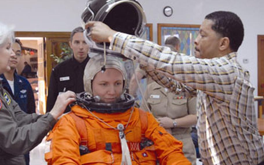 George Brittingham, member of a NASA training team, puts a spacesuit helmet on Lt. Lisa Steiner, a nurse at Naval Station Rota, during training class.