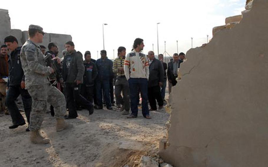 An American soldier monitors community project workers collecting their pay Monday at a patrol base on the border of Baghdad’s Sadr City district. U.S. forces in the area are overseeing the program despite a trend toward turning funding responsibilities over to the Iraqis.