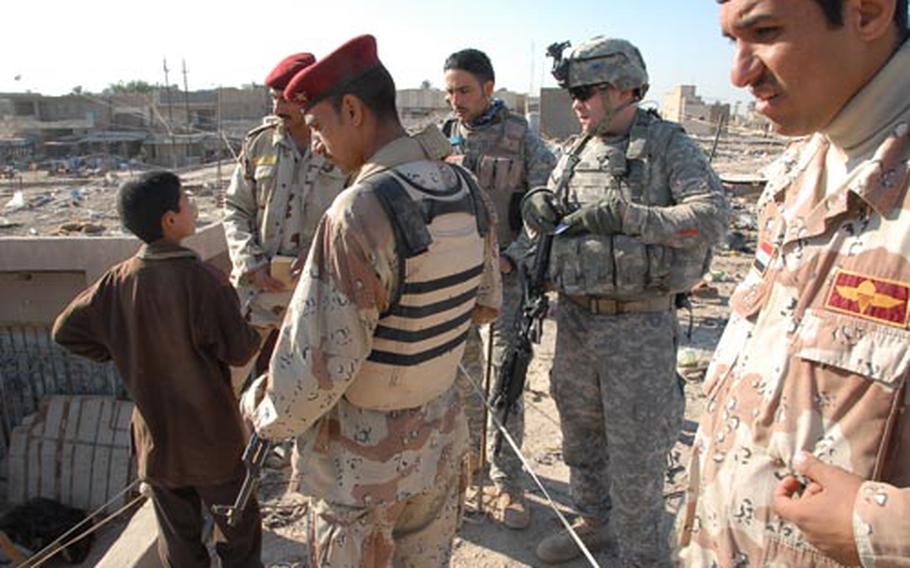 American and Iraqi troops check into reports of a weapons cache atop a building in Mahmudiyah on Tuesday.