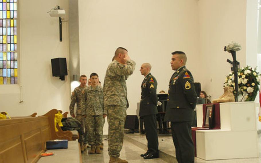 A soldier salutes a photo of Sgt. Brandon Augustus, a medic with the 47th Forward Support Battalion, during a memorial in Baumholder, Germany. Augustus died Dec. 11.