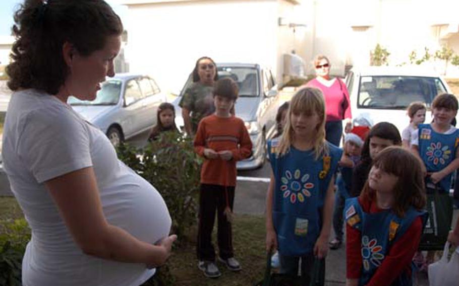 Amy Mancini, 34, right, shows off her tummy to curious Girl Scouts from Troop 436 who stopped by Dec. 10 to drop off meals at the Stork’s Nest on Camp Lester, Okinawa. She’s expecting twins.