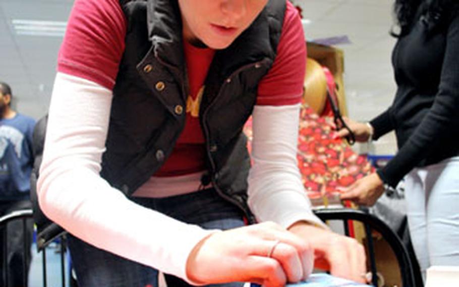 Samantha Tromly wraps an Apple iPod Shuffle at the Vogelweh Base Exchange on Tuesday. Members of the 3rd Air Force Top Cover Booster Club wrapped hundreds of holiday gifts for a small donation.