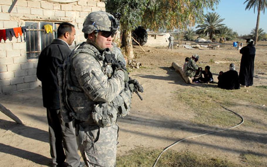 Capt. Tom Smith watches a group of women during a raid in the Mahmudiyah countryside Thursday. Intelligence reports said a wanted Al Qaeda operative and his bodyguards were staying at the farm but the women said only students and farmers had been there.