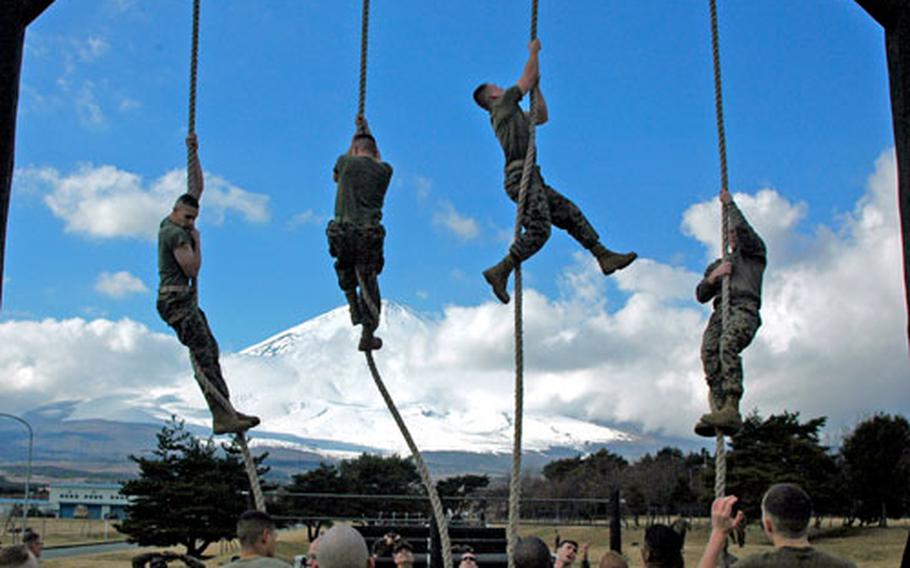 With Mt. Fuji in the background, Marines climb up a rope on the Camp Fuji obstacle course during a competition between the base&#39;s two companies. One-hundred eighty-five Marines call the remote mountainside installation their home.