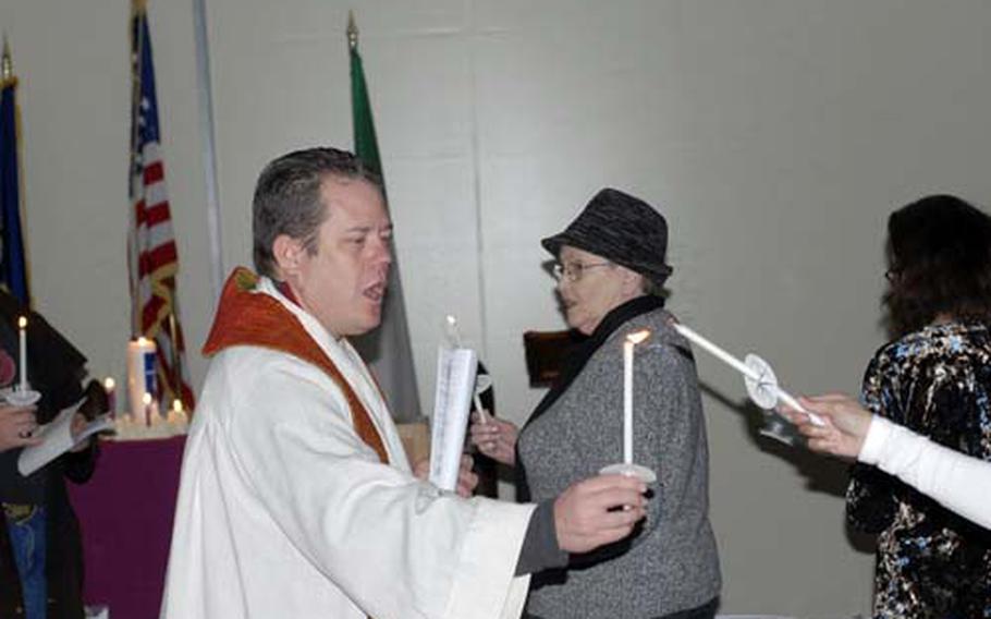 Navy Chaplain (Lt.) Doug McCormick lights the faithfuls&#39; candles during the Christmas Eve service at NSA Gaeta, Italy. About a dozen people attended the service, which could be the last Navy chaplain-led service in Gaeta after 41 years of services.