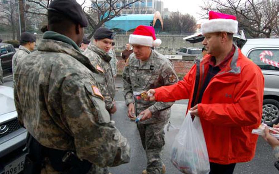 U.S. Army Garrison Yongsan director of emergency services Ricky Oxendine (right) and USAGY Command Sgt. Maj. Ralph Rusch hand out bags of candy to military police at Yongsan Garrison Wednesday as part of Operation Santa Express, a 10-year garrison tradition in which officials bring treats to emergency services personnel.