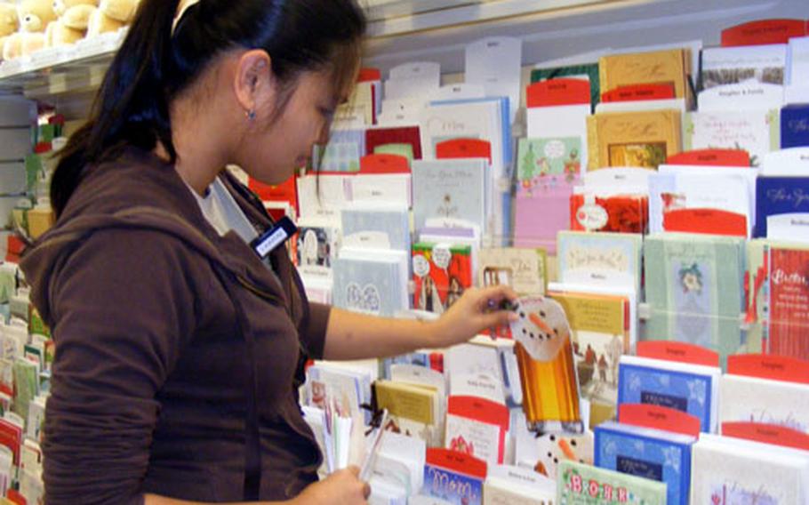 Hallmark Cards representaive Laarni Ruiz removes Christmas cards from the shelves of the AAFES store on Kadena Air Base Friday, making room for the next seasonal card selection.