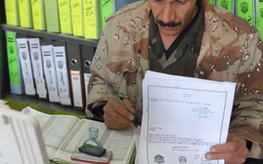 An Iraqi National Police soldier flips through a warrant request packet Dec. 20 at the Rusafa Area Command’s intelligence office at the old Ministry of Defense compound in Baghdad.