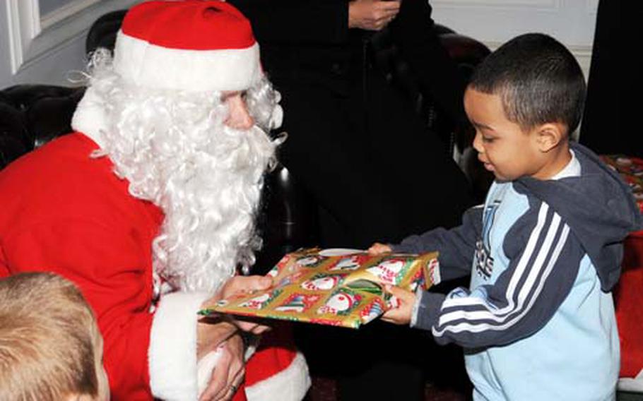 Three-year-old Kaidan Fleshman, son of Staff Sgt. Jerry Fleshman from the 100th Public Affairs Office, accepts a gift from Santa during the deployed spouses’ luncheon Dec. 7 at RAF Marham, England. Santa made a special appearance to hand out gifts.