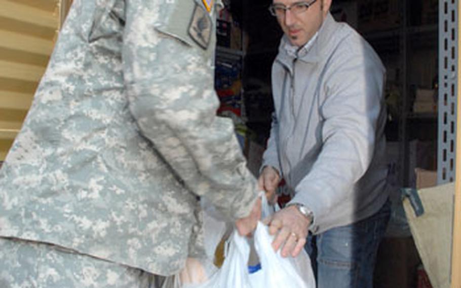 Carillo hands bags of donated supplies to Vicenzo Vario, who oversees a Vicenza, Italy food pantry run by the local Catholic archdiocese.