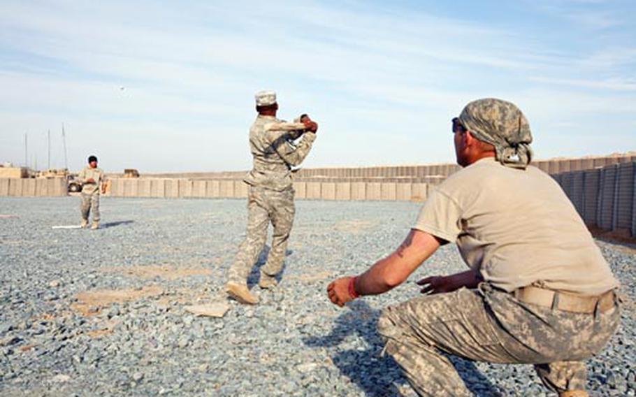 Sgt. Jose Dalmasi, 31, of Carolina, Puerto Rico, slaps a home run during an afternoon baseball game played by Company B, 62nd Engineers, during a lull in the construction of a combat outpost in Maiwand District, Afghanistan. The other two soldiers are Staff Sgt. Jacinto Aguero, 26, of Dallas, Texas, (pitching) and Sgt. Thomas Deaton, 28, of Martins Ferry, Ohio (catching).