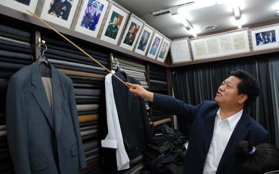 Park Wan-yong, owner of New York Tailor in Itaewon, points to pictures of the former U.S. Forces Korea commanders who were his customers. Park said he will lose many of his customers when the base closes in 2012.