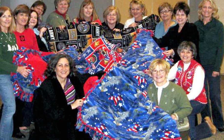 Linda Ferrara, far left, and her friends display some of the blankets they made for troops recovering at Landstuhl Regional Medical Center.