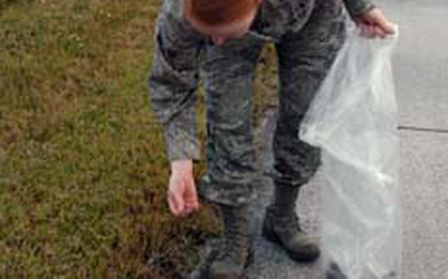 Senior Airman Jennifer Coviello, of the 18th Aerospace Medicine Squadron, picks up a debris along the grassy area at one of the runways at Kadena Air Base in Okinawa.