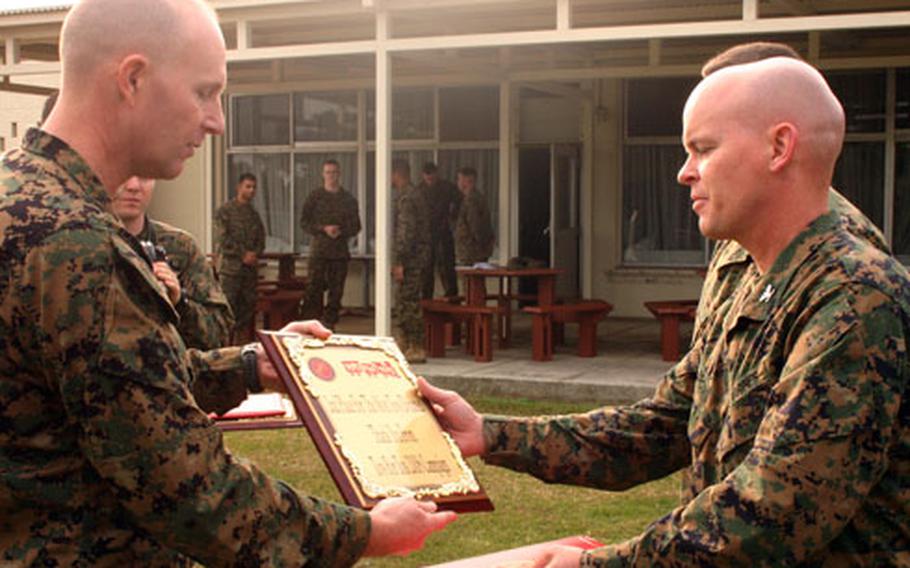 Lt. Col. David Edson, left, the III Marine Expeditionary Force Reserve liaison officer, presents a plaque to Col. Raphael Brown, commander of Marine Air Control Squadron 4, recognizing the unit for donating the second-largest number of toys during the competition on Okinawa