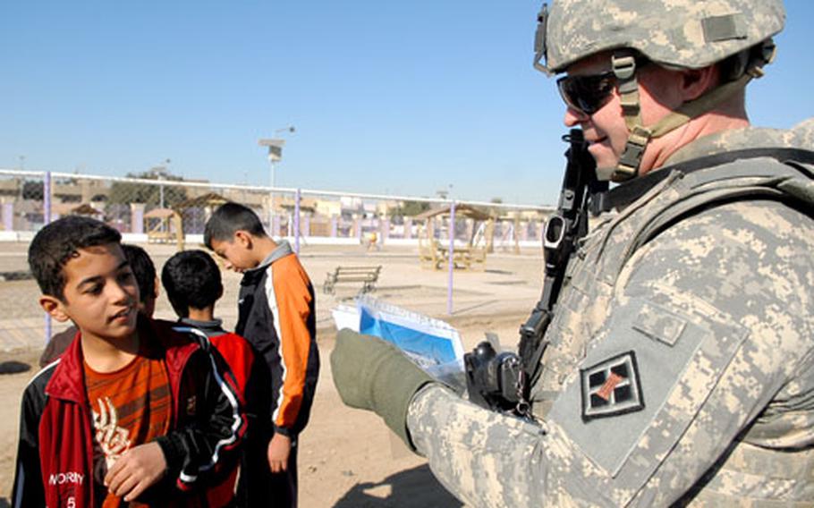Col. Jared Olsen, commander of Task Force Gold, the 926th Engineer Brigade’s Sadr City effort, gives pictures from a park opening to Iraqi children Wednesday at al-Faoo Park in Baghdad’s Sadr City district. Building parks like this wins people over and denies enemy fighters the use of key terrain, American troops say.
