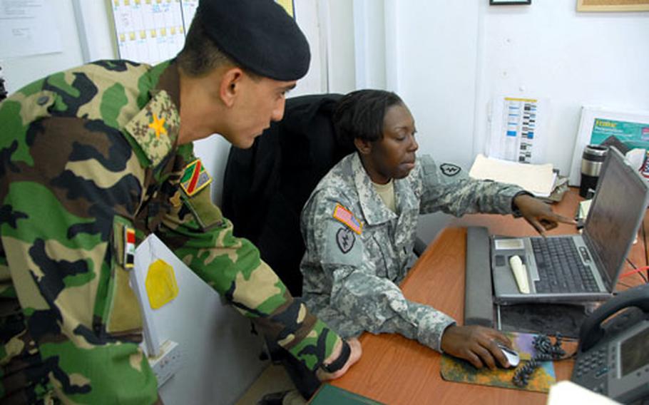1st Lt. Nakesha Moultrie, of Company A, 225th Brigade Support Battalion, 2nd Stryker Brigade Combat Team, 25th Infantry Division, explains a supply diagram to Lt. Abbas Fadhel, an embedded Iraqi transportation platoon commander, on Thursday.