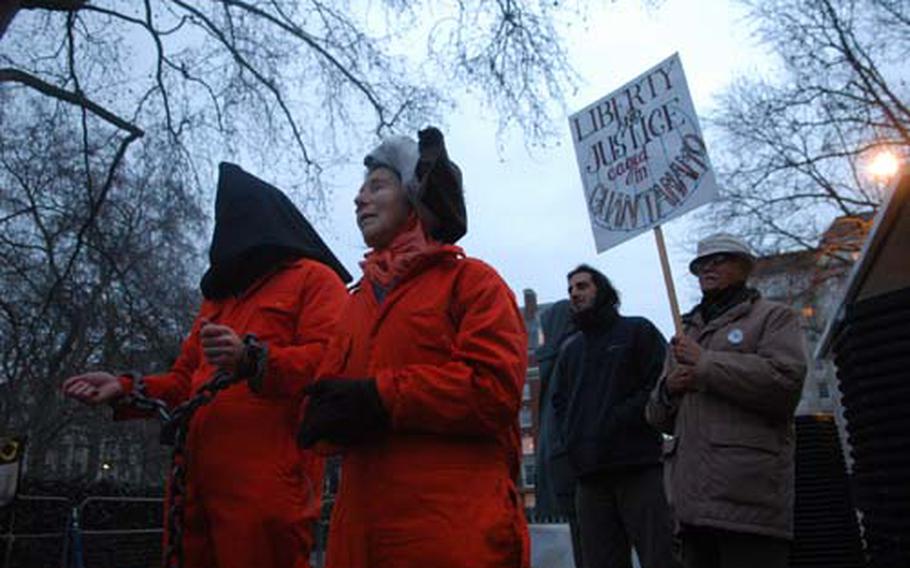 David Viesnik, left, and Doreen Brown stand in orange jump suits and shackles during a rally outside the U.S. Embassy on Sunday.
