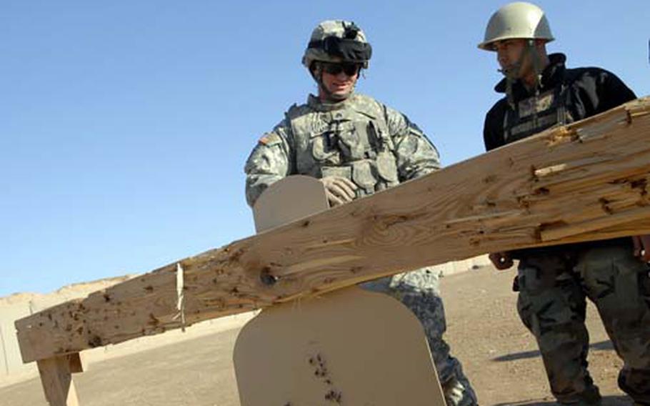 Sgt. Christopher Mannies, left, with the 3rd Infantry Brigade Combat Team, 25th Infantry Division Brigade Support Battalion, reviews an Iraqi soldier&#39;s target shooting during a training session Tuesday at Contingency Operating Base Speicher outside Tikrit, Iraq.