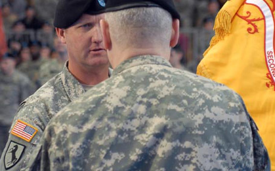 Left: Outgoing 2nd Stryker Cavalry Regiment commander Col. John RisCassi (center, facing camera) hands the unit colors to U.S. Army Europe commander Gen. Carter Ham, while new 2nd Cav commander Col. James R. Blackburn Jr. prepares to receive them at Grafenwöhr, Germany, on Tuesday. Above: Blackburn, facing camera, takes the unit colors from Ham.