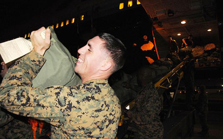 Above: Lance Cpl. Wayne Jarvis helps unload gear from the belly of the plane that brought his unit to Okinawa from Camp Pendleton, Calif. Below: More than 300 Marines of the 3rd Battalion, 5th Marine Regiment load buses at the Kadena Air Base flightline Wednesday.