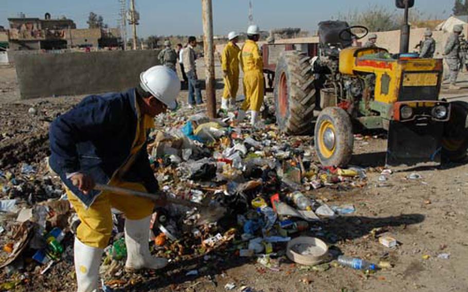 Workers scoop up trash in central Abu Ghraib, Iraq. Garbage cleanup is part of a major effort by the Iraqi government, the U.S. and nongovernmental organizations to revitalize the war-torn area.