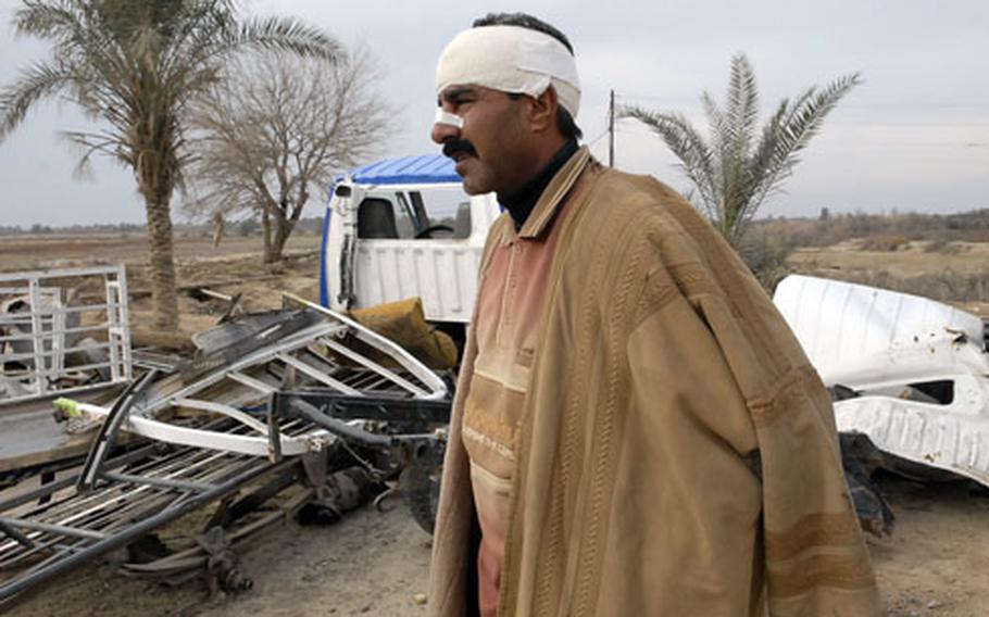 Ishmael Abdullah Jari stands by the twisted remains of his truck, recently blown up by a roadside bomb.