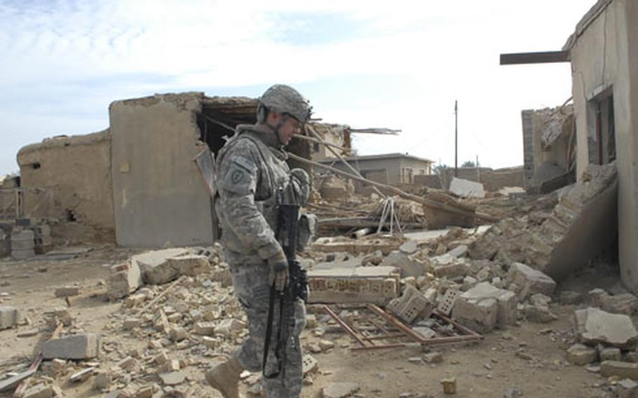 Spc. James Wallace walks past the rubble of a home in Karab, one of many towns in Diyala province terrorized by insurgents.